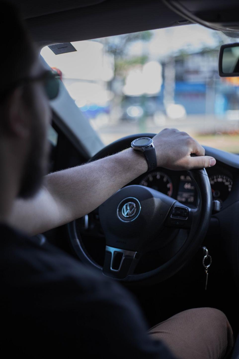 a man driving a car with his hand on the steering wheel